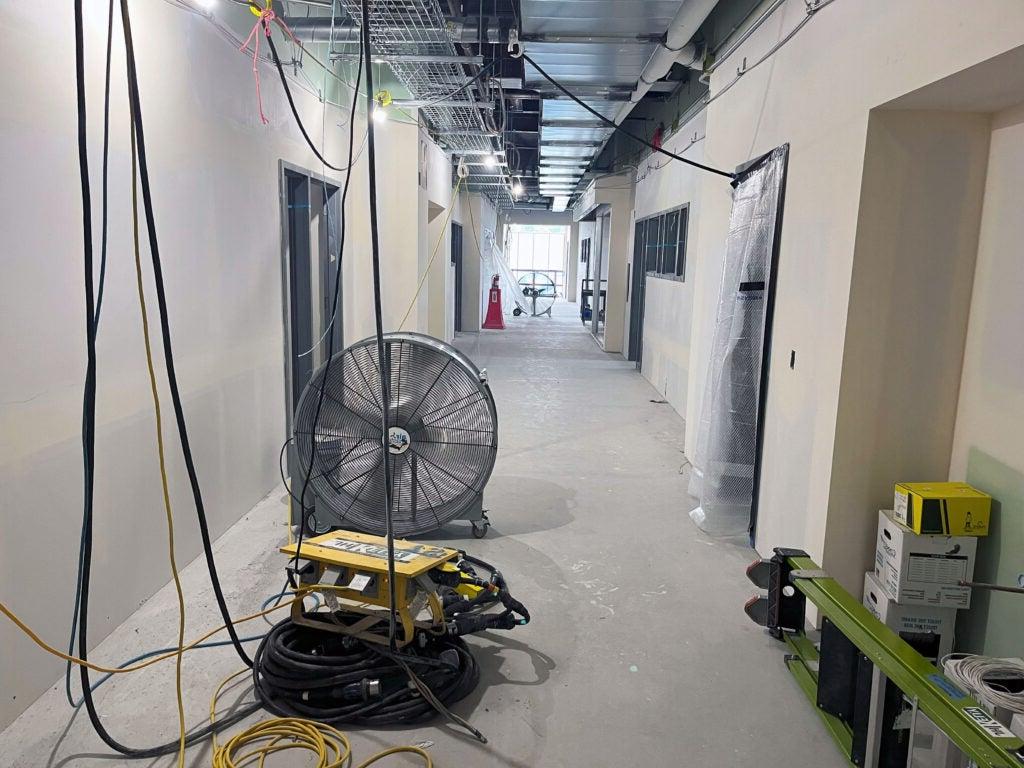 a hallway under construction with a large fan on the floor