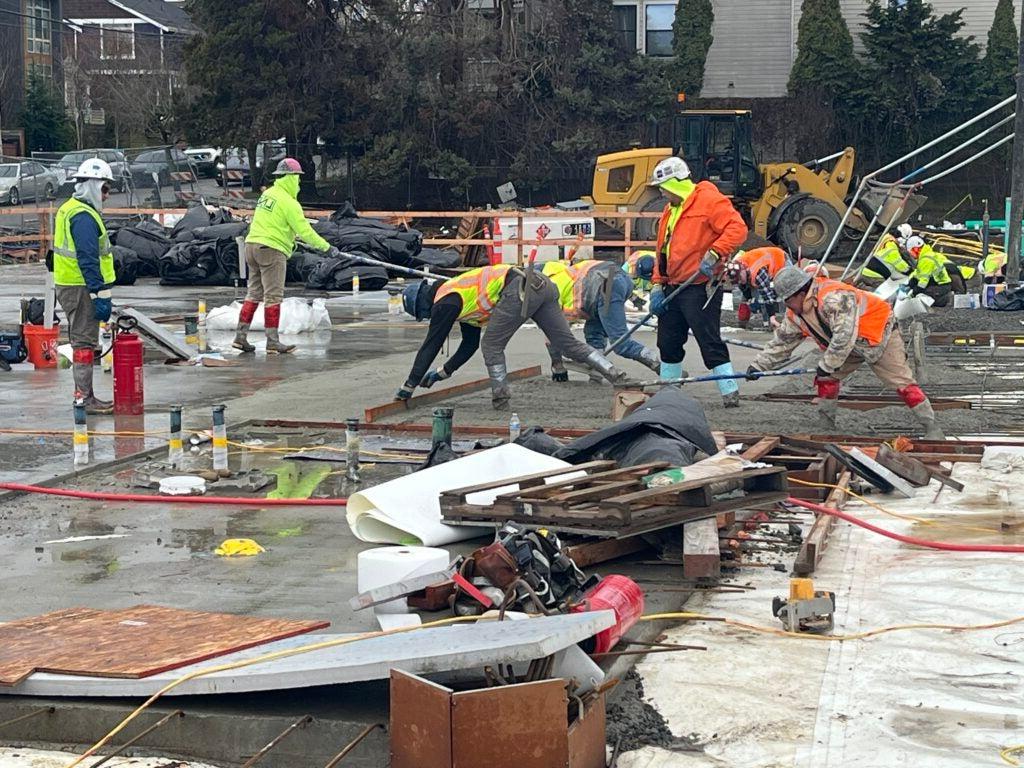 workers are spreading concrete at a construction site